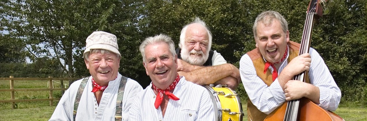 The Wurzels band sitting in a field.