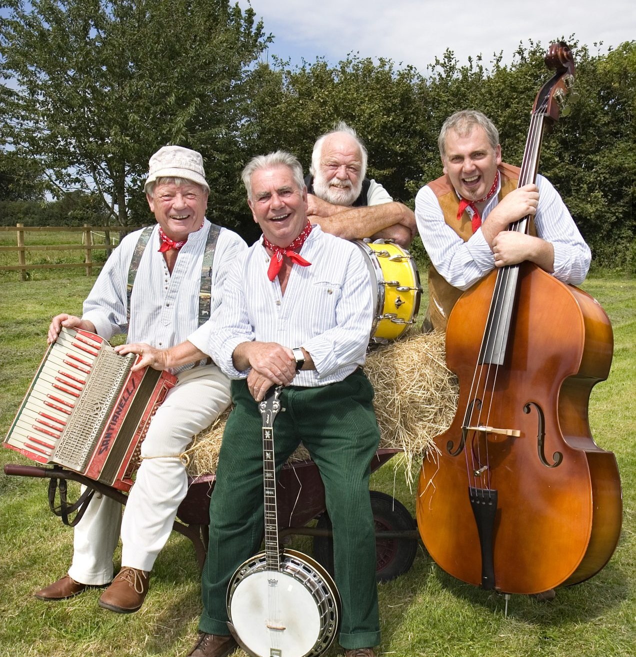 The Wurzels band sitting in a field with their instruments